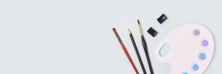 Banner with watercolor palette and paintbrushes on a blue background. Artistic concept with copyspace.の写真素材