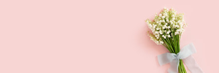 Header with bouquet of lily of the valley flowers tied with ribbon. Gift for Mothers, Womans day on a pink background. Spring concept with copy space.の写真素材