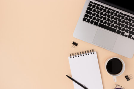 Workplace with laptop, coffee and stationery on a beige background. E-learning, online education concept with copy space.の写真素材