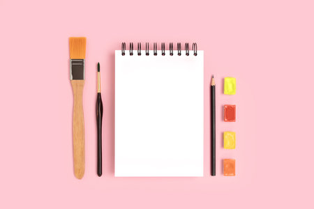 Blank notepad mockup and tools for painting on a pink background. Organized artistic workspace with copyspace.の写真素材