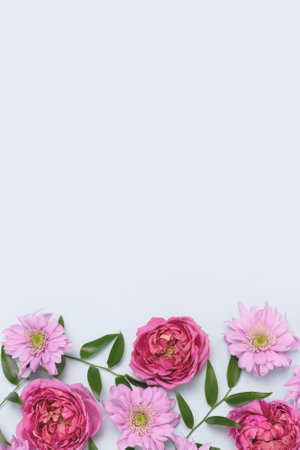 Frame made of aster, rose flowers and green leaves texture on a blue pastel background. Springtime floral composition with copyspace.の写真素材