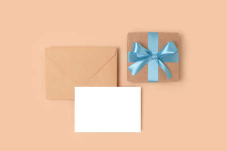 Envelope, empty paper sheet mockup and gift box on a beige background. Present and greeting card...