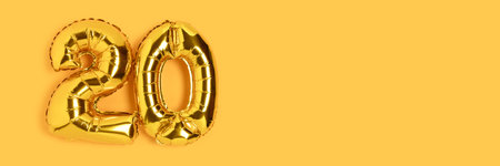 Banner with number 20 golden balloons with place for text. Twenty years anniversary celebration concept on a yellow background.の写真素材