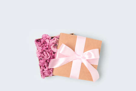 Gift with a tied bow. Open box with flowers inside. Present for springtime holidays on a blue background.の写真素材