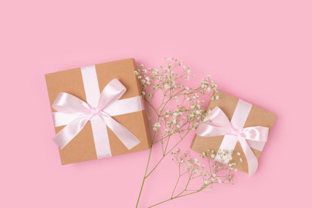 Gift boxes with a tied ribbons and branch of gypsophila flower on a pink background. Congratulation concept with copyspace.の写真素材