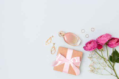 Layout of flowers bouquet, gift with tied bow, feminine accessories on a blue background. Tenderness female composition with copyspace.の写真素材