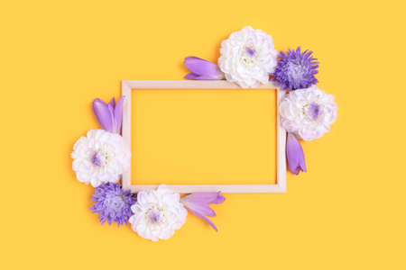 Top view of flower border frame made of dahlia on a bright yellow background. Greeting card template...