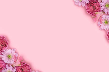 Frame made of rose and aster flowers on a pink pastel background with copyspace. Festive...