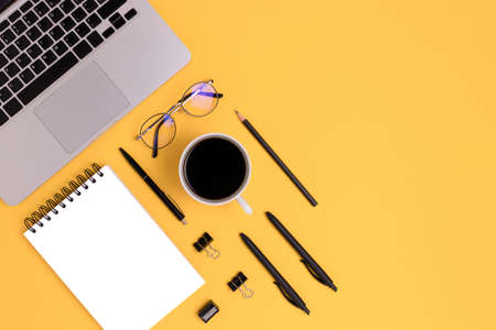 Organized workspace with coffee, laptop and office supply on a yellow background. Online education, remote job concept with copy space.の写真素材