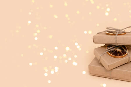 Pile of gift boxes on a beige background with glowing gold bokeh. Holidays preparation composition with place for your design.の写真素材