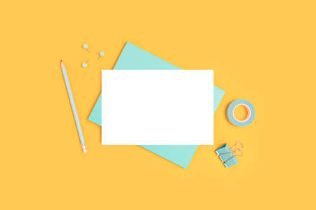 Blank paper card mockup and stationery on a yellow background. Minimalistic business workspace.