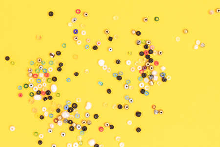 Composition with colorful beads scattered on a yellow background.の写真素材