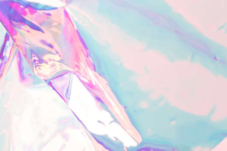 Defocused holographic background. Blurred colorful texture of wrinkled foil in blue and pink colors.