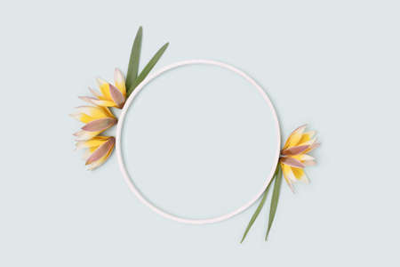 Round frame made of wild yellow tulip flowers and green leaves on a blue pastel background.