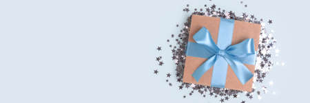 Banner with gift box with tied ribbon and silver confetti on a blue background.の写真素材