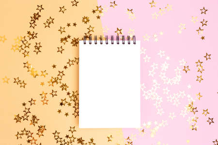 Empty notebook mockup with glittering stars confetti on a pink and gold background.
