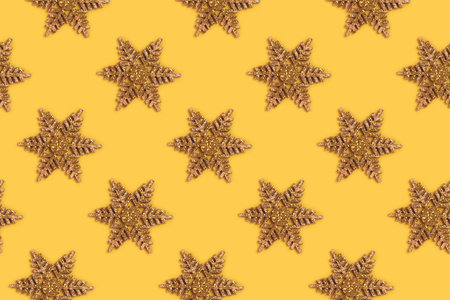 Golden glittering snowflakes pattern on a yellow background. Christmas composition.
