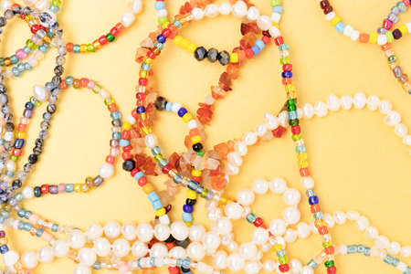 Necklaces and bracelets made from multicolored beads and pearls on a golden background.
