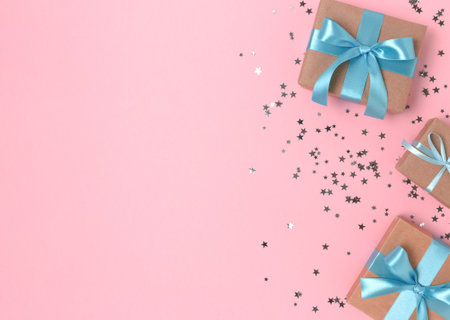 Frame made of gift boxes with blue ribbons and silver confetti on a pink pastel background.の写真素材