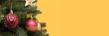 Banner with shiny Christmas decorations. Colorful New Year ornaments in front of yellow background with copy space.の写真素材