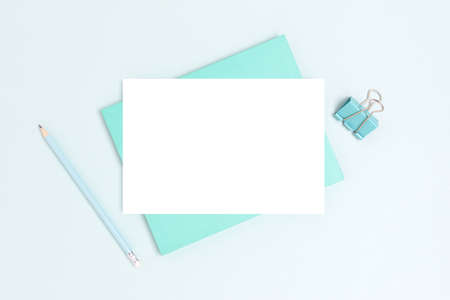 Blank paper card mockup and stationery on a blue background. Monochrome business workspace.の写真素材