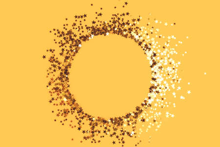 Round frame made of gold colored stars confetti on a yellow background.の写真素材