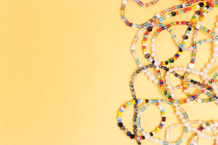 Necklaces and bracelets made from beads and pearls on a golden background with copyspace.