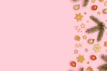 Frame made of Christmas toys and fir tree branches pattern on a pink pastel background. Festive layout with place for text.の写真素材