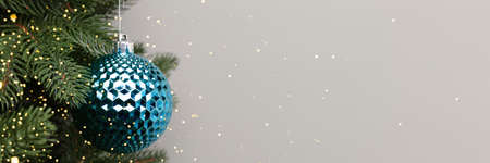 Banner with blue metallic Christmas bauble. New Year decoration in front of gray background with...