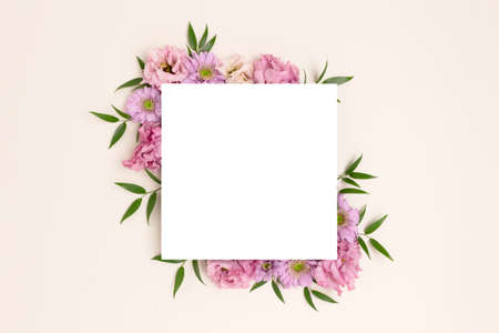 Paper card with border frame made of eustoma flower on a beige background. Springtime composition for 8 March with copyspace.の写真素材
