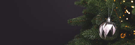 Banner with silver metallic Christmas toy. Festive decoration in front of black background with copyspace.の写真素材