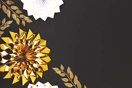 Golden paper fans and glittering branches on a black background. Festive concept with copy space.の写真素材