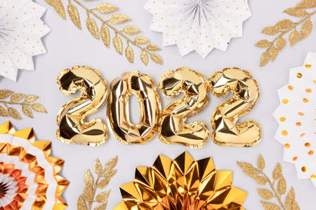 2022 inflatable golden balloons and glittering decorations. New Year's concept on a blue background.