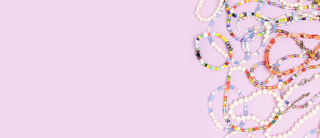 Necklaces and bracelets made from multicolored beads and pearls on a purple background with copyspace.の写真素材