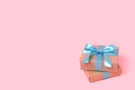 Pile of gift boxes in front of pink background. Present with blue tied ribbon. Congratulation concept with copyspace.の写真素材