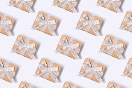 Repetitive pattern made from gift boxes with silver ribbons. Creative concept on a blue background.