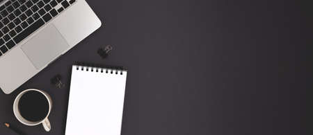 Banner with coffee, laptop and office supply on a black background. Online education, remote job workspace.の写真素材