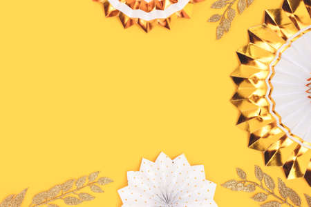 Golden paper fans and glittering branches on a yellow background. Festive concept with copyspace.の写真素材