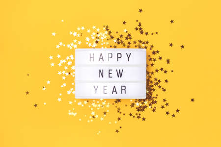 Happy New Year. Lightbox and golden stars confetti on a yellow background.の写真素材