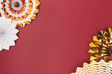 Border frame made of gold colored paper fans on a red background.