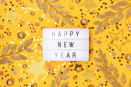 Happy New Year. Lightbox and golden glittering decorations on a yellow background.の写真素材
