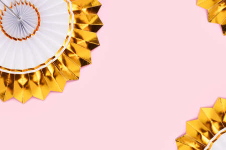 Frame made of golden paper fans on a pink background. Festive composition with copyspace.の写真素材