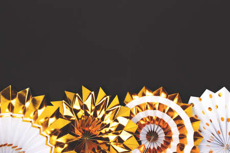 Row of golden paper fans on a black background. Festive layout with copyspace.