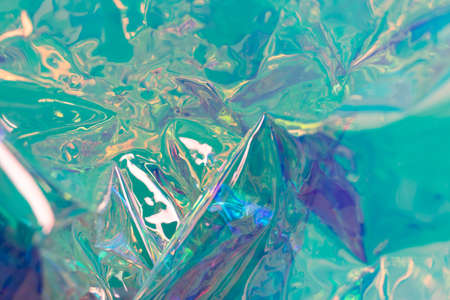 Turquoise blurred holographic background. Wrinkled foil surface. Defocused surreal texture.の写真素材