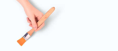 Banner with female hand hold paintbrush on a blue pastel background. Repair concept with copyspace.の写真素材