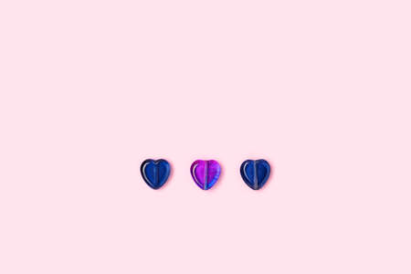 Three purple beads in a heart shape on a pink background. Minimal composition with copy space.の写真素材