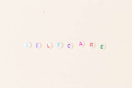 Self care. White round beads with colorful letters on a beige background.の写真素材