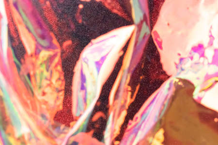 Blurred holographic background. Defocused multicolored texture of wrinkled foil in red colors.の写真素材