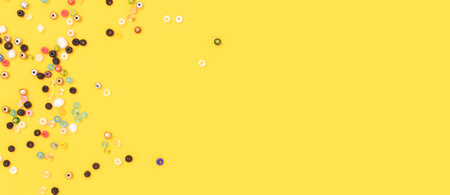 Banner with multicolored beads scattered on a yellow background with copyspace.
