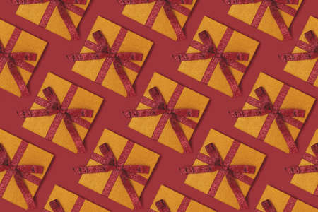 Repetitive pattern made from gift boxes with ribbons. Creative concept on a red background.の写真素材
